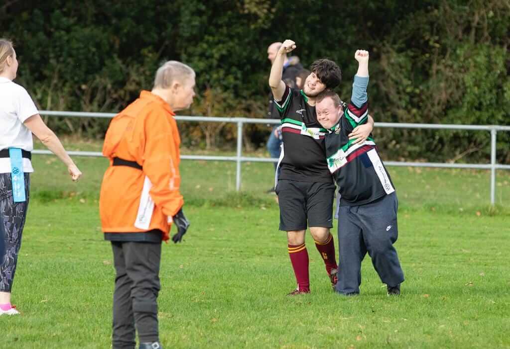 2 DLSP rugby players on the pitch sharing a hug